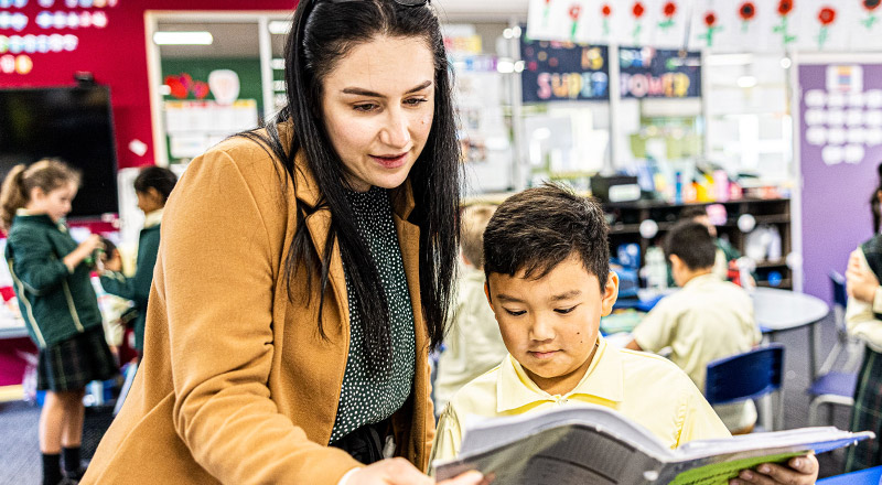 Dedicated teacher and student reading a book at St Aidan's Catholic Primary School Rooty Hill