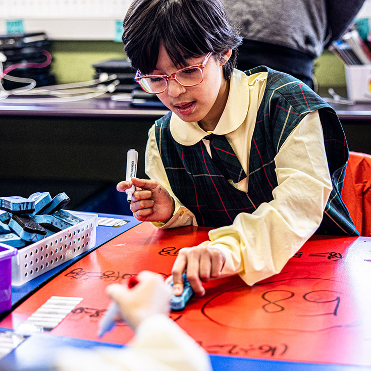 Student writing on whiteboard desk at St Aidan's Catholic Primary School Rooty Hill
